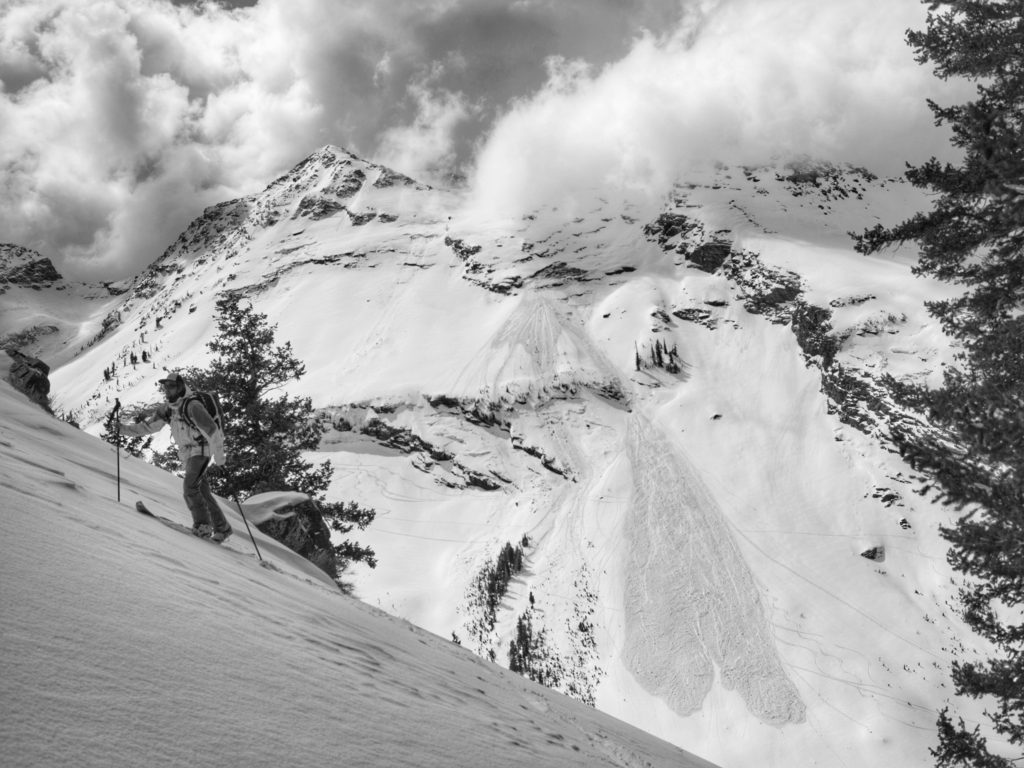 Skinning up with an avalanche slide path in the background.