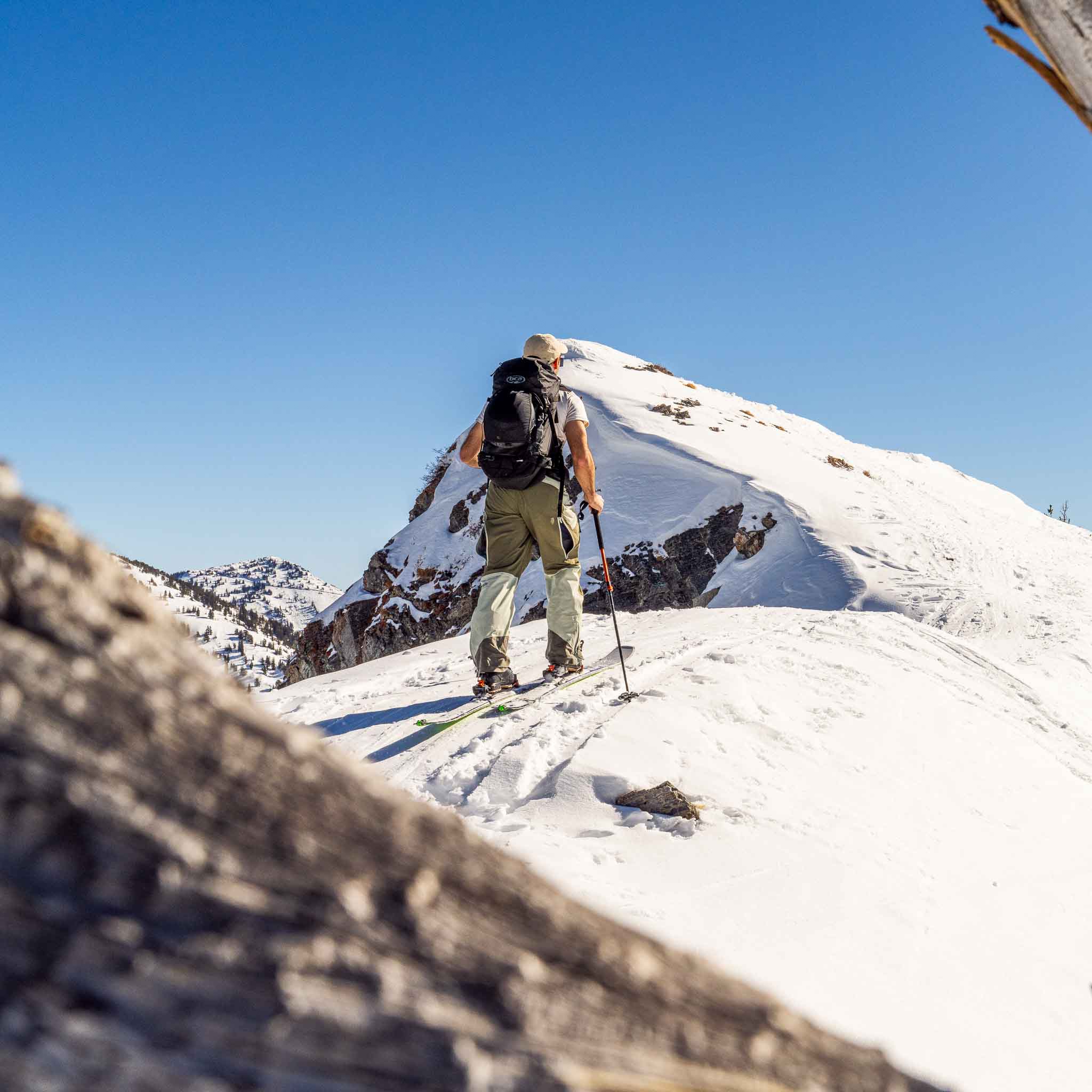Skier using Voile Hyper Manti skis to skin up a snowy ridge under clear blue sky